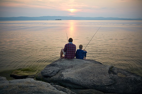 Father and son sitting on a rock fishing