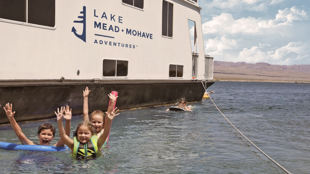 Kids playing in the water next to a Lake Mead Mohave Adventures houseboat