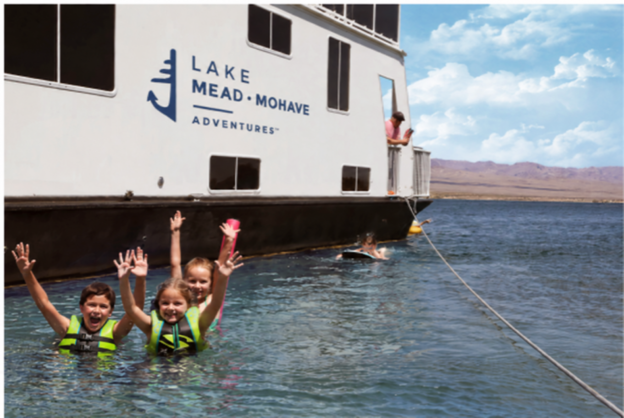 Kids playing in the water next to a houseboat
